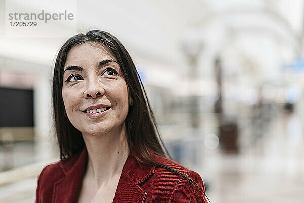 Nachdenkliche Geschäftsfrau  die in einer U-Bahn-Station lächelnd wegschaut