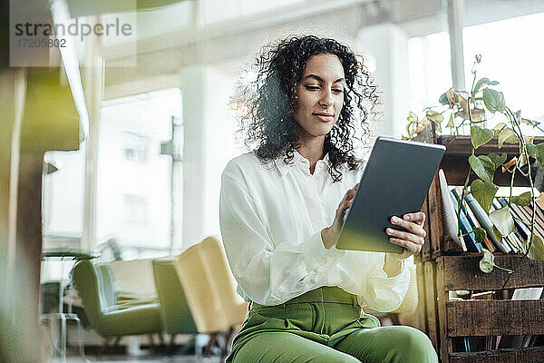 Junge Geschäftsfrau  die ein digitales Tablet benutzt  während sie in einem Café sitzt