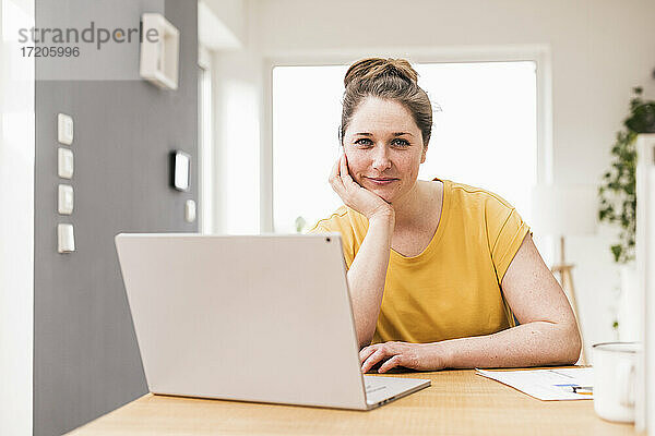 Unternehmerin mit Laptop am Schreibtisch sitzend