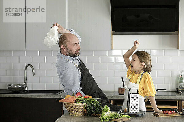Verspielter Vater und Tochter geben sich High-Five  während sie in der Küche zu Hause stehen