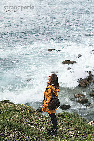 Junge Frau steht auf einem Felsen am Meer