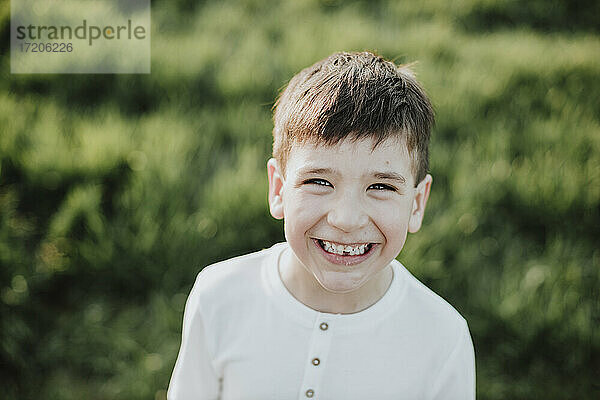 Lächelnder Junge auf einer Wiese an einem sonnigen Tag