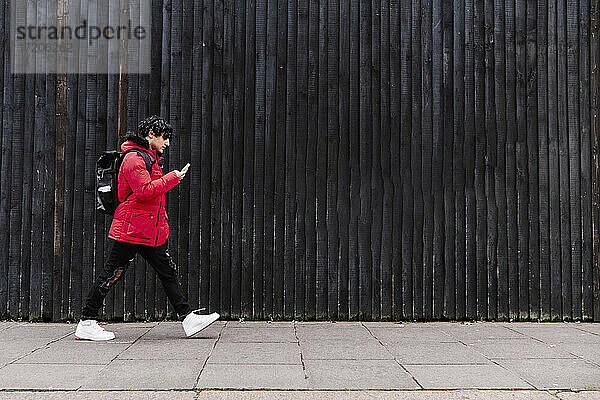 Mann benutzt Mobiltelefon beim Gehen auf dem Fußweg