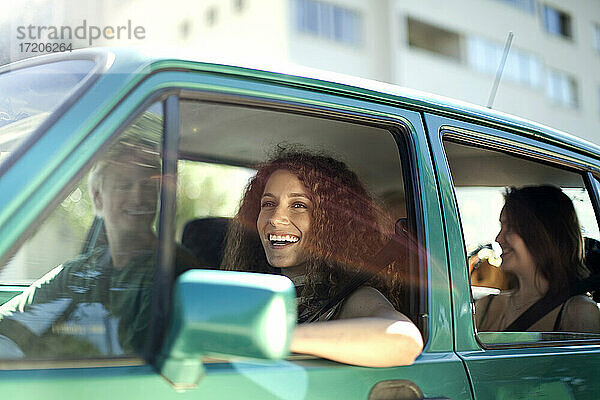 Lächelnde Frau schaut weg  während sie mit Freunden im Auto sitzt