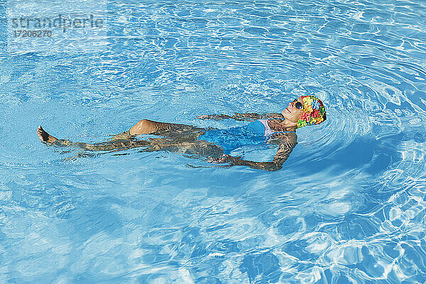 Frau entspannt sich im klaren blauen Schwimmbad