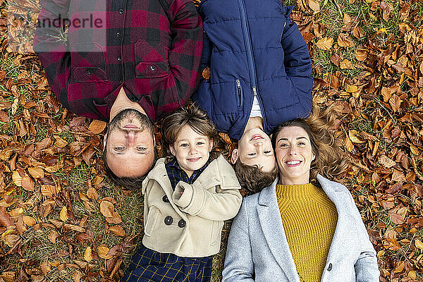 Lächelnde Familie auf einem gefallenen Blatt im Wald im Herbst liegend