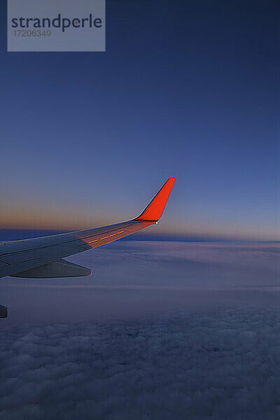 Flügel eines Verkehrsflugzeugs fliegen gegen den Himmel in der Abenddämmerung