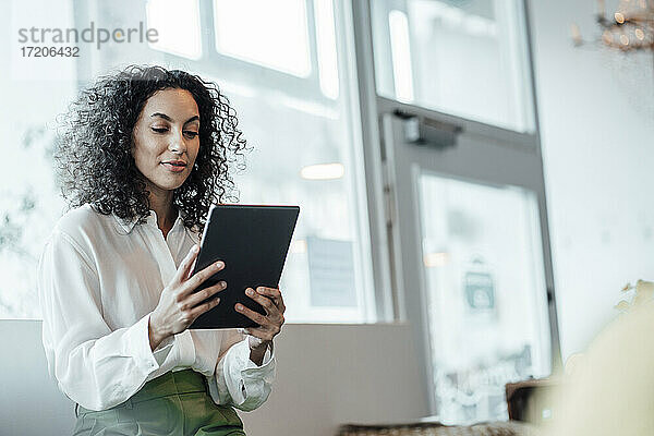 Geschäftsfrau  die ein digitales Tablet benutzt  während sie in einem Café sitzt