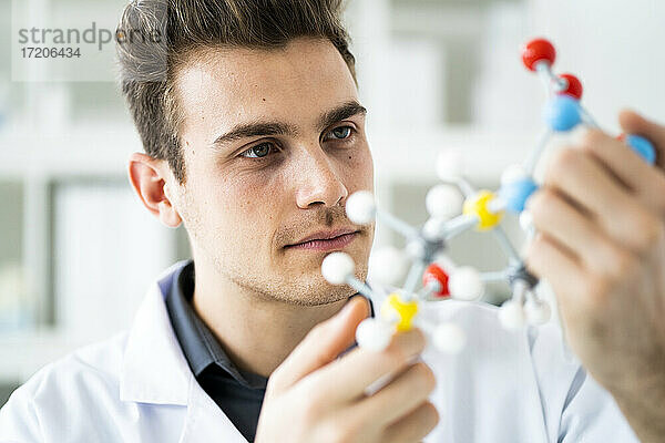 Konzentrierter männlicher Wissenschaftler  der eine molekulare Struktur im Labor untersucht