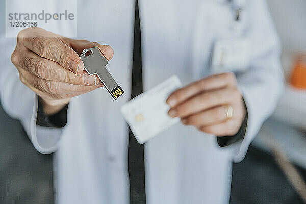 Männlicher Arzt  der einen USB-Stick hält  während er in einer Klinik steht