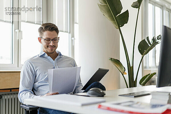 Männlicher Unternehmer mit Dokument und digitalem Tablet im Büro
