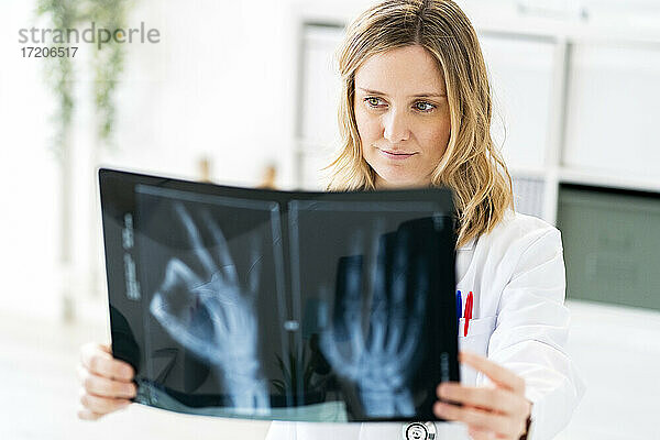 Blonde Radiologin bei der Analyse von Röntgenbildern in einer medizinischen Klinik