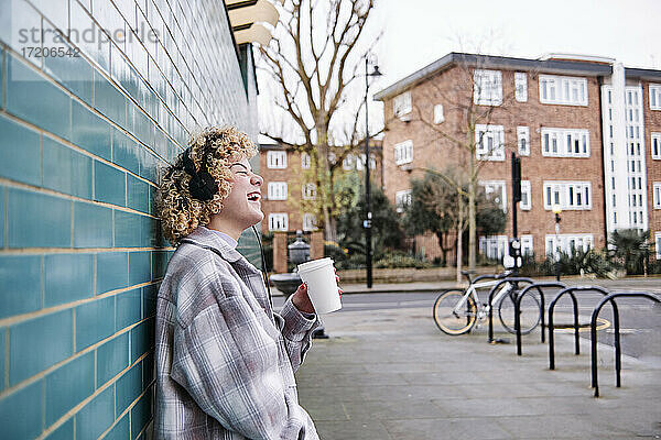 Fröhliche Frau lacht bei einem Kaffee auf dem Fußweg