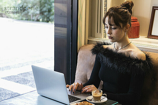 Geschäftsfrau arbeitet am Laptop  während sie in einem Café sitzt