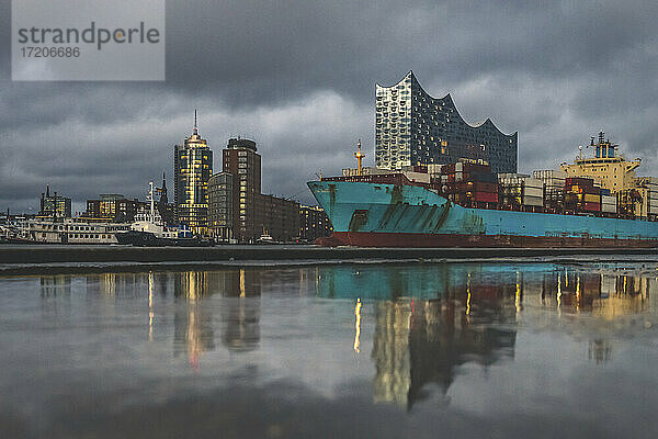 Deutschland  Hamburg  Anlegertheater  Elbphilharmonie und sich im Wasser spiegelndes Containerschiff