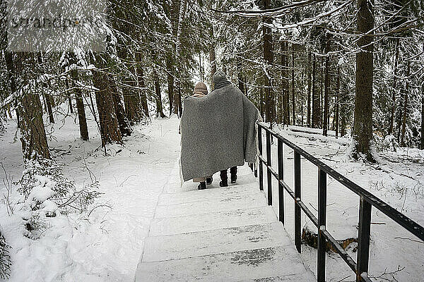 Paar in Decke gehüllt auf Treppe im Wald