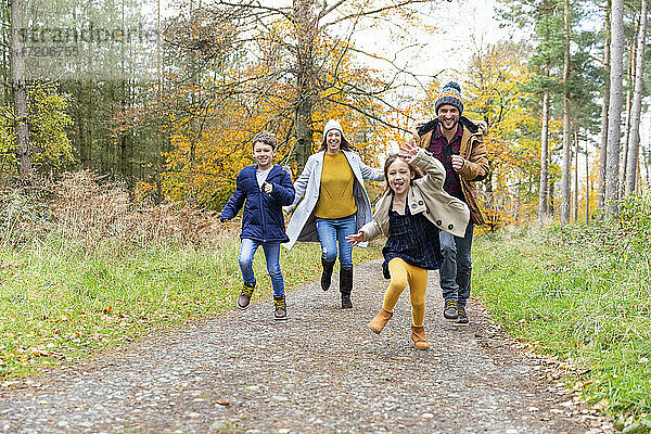 Glückliche Familie beim gemeinsamen Laufen auf einem Waldweg