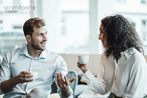 Lächelnde Geschäftsleute unterhalten sich bei einem Kaffee in einem Café