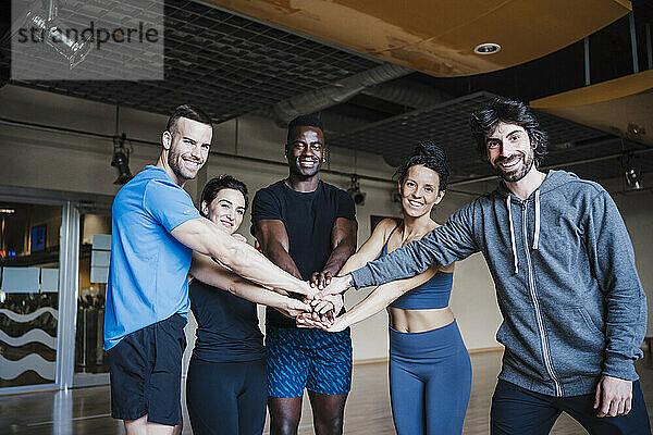 Lächelnde multiethnische Gruppe von Sportlern  die in einer Turnhalle zusammensitzen
