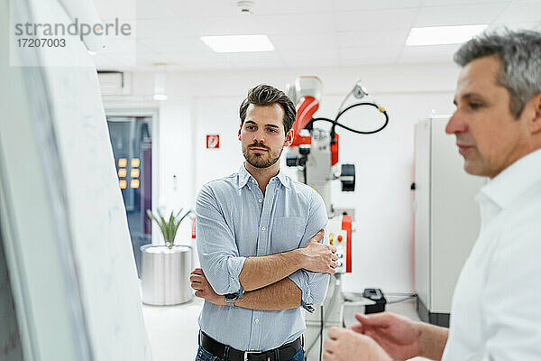 Männliche Unternehmer schauen auf eine weiße Tafel in einer Fabrik