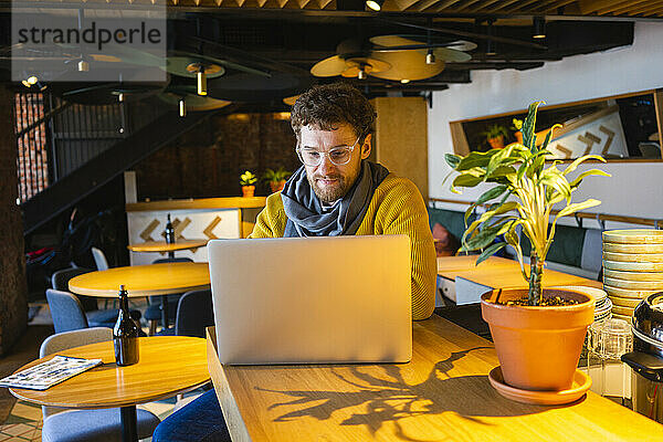 Gut aussehender Geschäftsmann  der einen Laptop benutzt  während er in einem Café sitzt