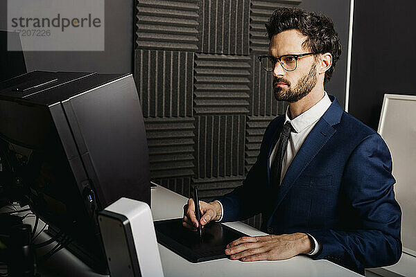 Geschäftsmann mit Grafiktablett am Schreibtisch im Büro