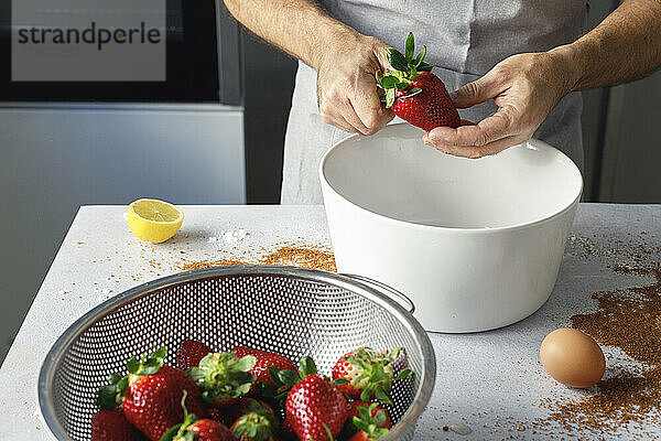 Hände eines Mannes  der frische Erdbeeren zubereitet