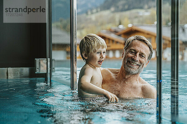 Lächelnder Vater mit Sohn im Infinity-Pool eines Hotels