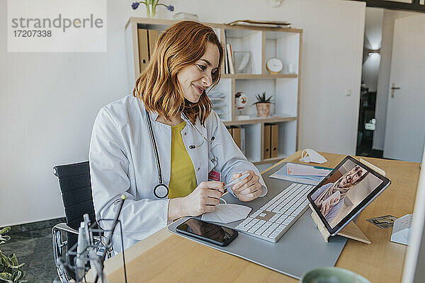 Ein Arzt hört einem Patienten bei einem Videogespräch über ein digitales Tablet zu  während er im Büro sitzt