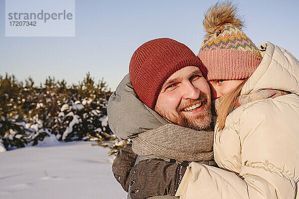 Lächelnder Vater  der seine Tochter in warmer Kleidung im Winter umarmt