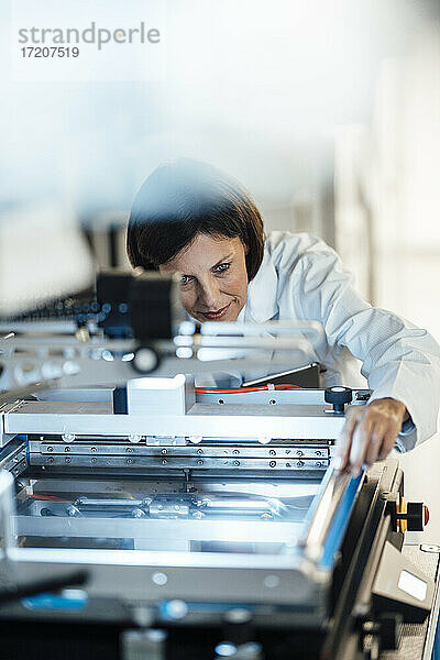 Reife Geschäftsfrau  die Maschinen in der Beleuchtungsindustrie analysiert