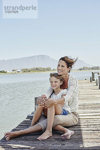 Lächelnder Junge mit Mutter auf dem Pier sitzend