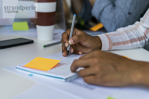 Unternehmerin schreibt Notizen in Tagebuch im Büro