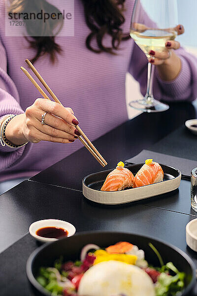 Ältere Frau isst Sushi mit Stäbchen im Restaurant