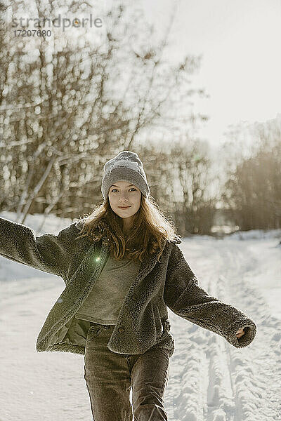 Porträt eines schönen Teenagers  der durch den Schnee auf die Kamera zugeht