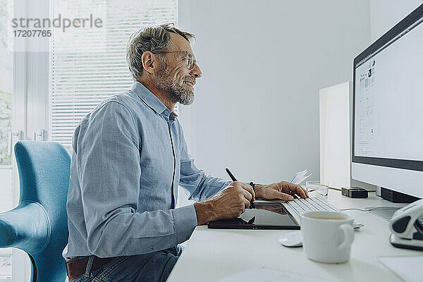 Geschäftsmann beim Schreiben auf einem digitalen Tablet während der Arbeit im Home Office