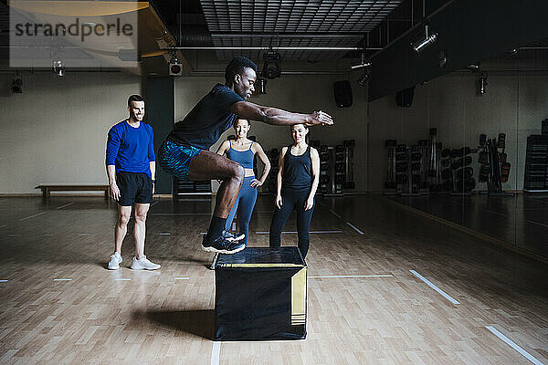 Junger männlicher Sportler  der im Fitnessstudio auf einen Kasten springt