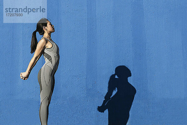 Frau streckt Hände an blauer Wand aus