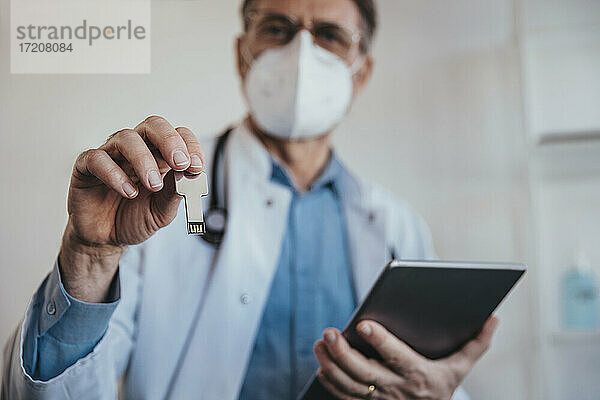 Arzt hält USB-Stick und digitales Tablet in der Hand  während er in der Klinik steht