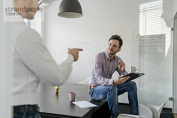 Männlicher Unternehmer plant mit einem Kollegen während einer Besprechung im Büro