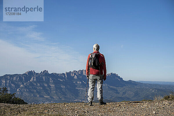 Älterer Wanderer mit Rucksack bewundert die Aussicht auf den Montserrat  während er auf dem Berg bei Sant Llorenc del Munt i l'Obac  Katalonien  Spanien  steht