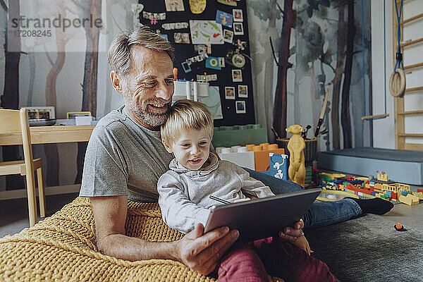Lächelnder Vater mit süßem Sohn E-Learning auf digitalem Tablet