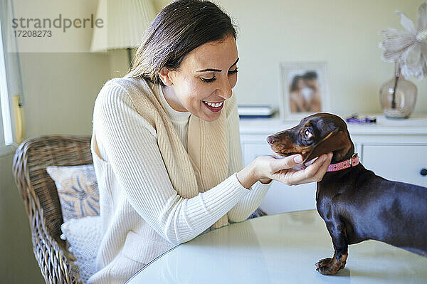 Verspielte Frau bewundert den Hund am Wohnzimmertisch
