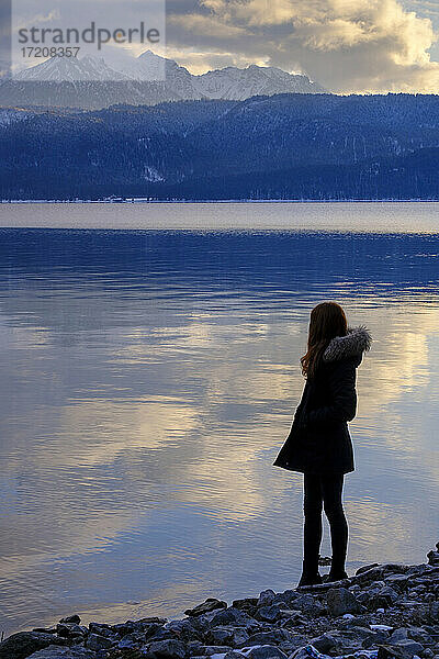 Deutschland  Bayern  Junge Frau mit Blick auf den Walchensee bei Sonnenuntergang