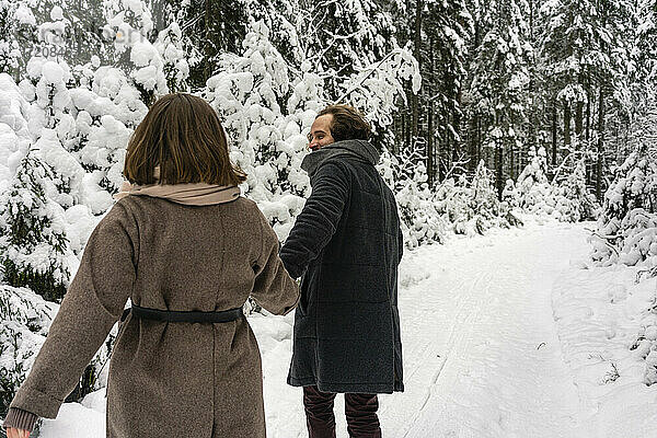 Freund hält die Hand seiner Freundin beim Spaziergang auf einem Waldweg