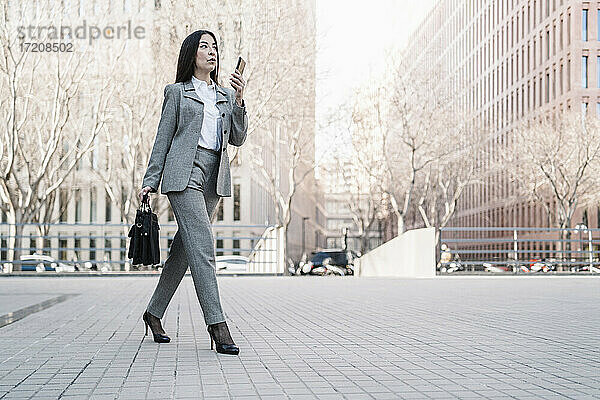 Reife Geschäftsfrau im Gespräch auf dem Smartphone beim Spaziergang in der Stadt