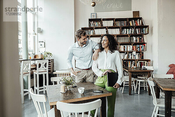 Geschäftsleute  die lächelnd am Tisch eines Cafés stehen