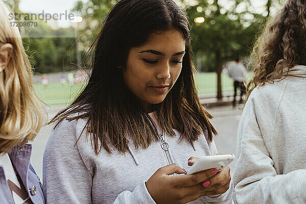 Teenager-Mädchen mit Smartphone mit weiblichen Freunden in Skate-Park