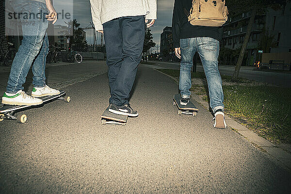 Tiefschnitt eines männlichen Freundes beim Skateboardfahren in der Dämmerung