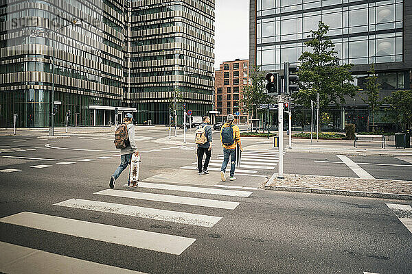 Rückansicht von männlichen Freunden beim Überqueren der Straße in der Stadt